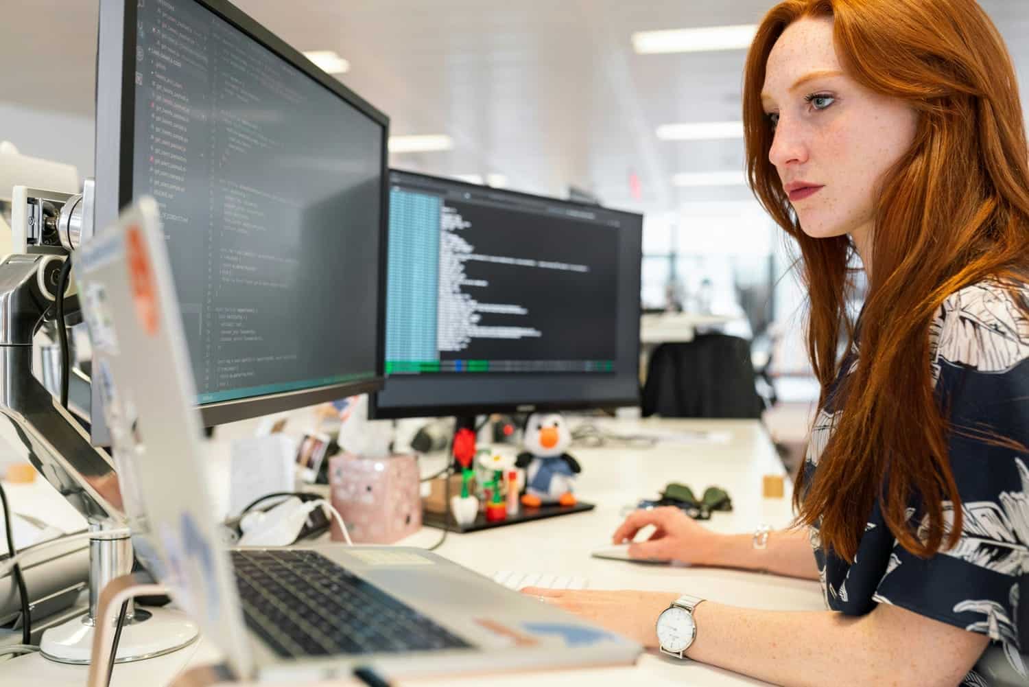 Professionnelle devant deux écrans d’ordinateur, illustration des métiers spécialisés dans les outils numériques et l’IA