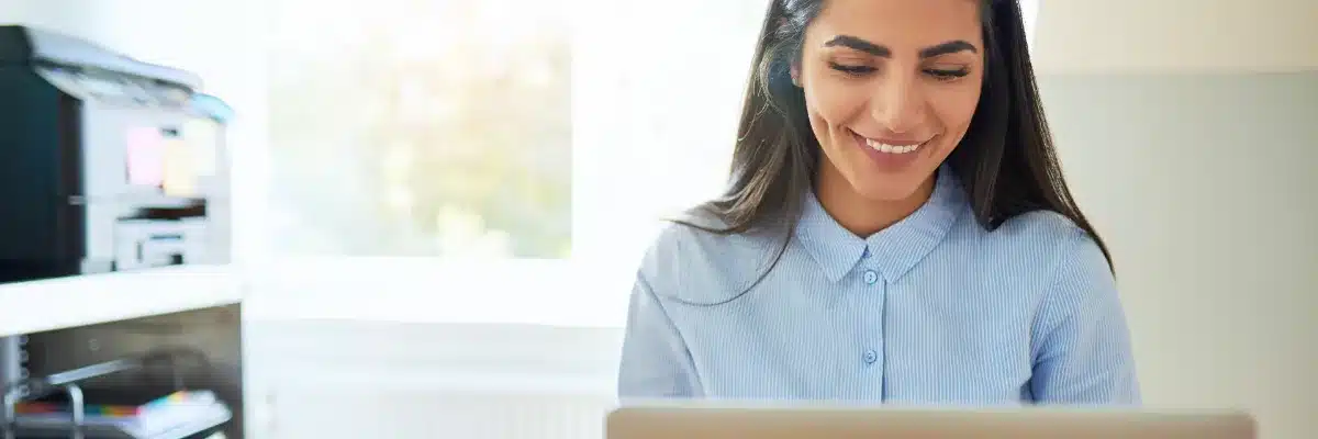 Une dirigeante cherche un prestataire sur son ordinateur, dans son bureau